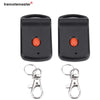 Black garage door remote control with a dip switch programming feature and attached metal key ring.