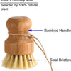 A wooden bamboo dish scrub brush with a natural sisal bristle handle and bristles.