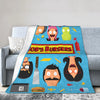 A colorful cartoon-themed throw blanket featuring characters from Bob's Burgers on a gray sofa.