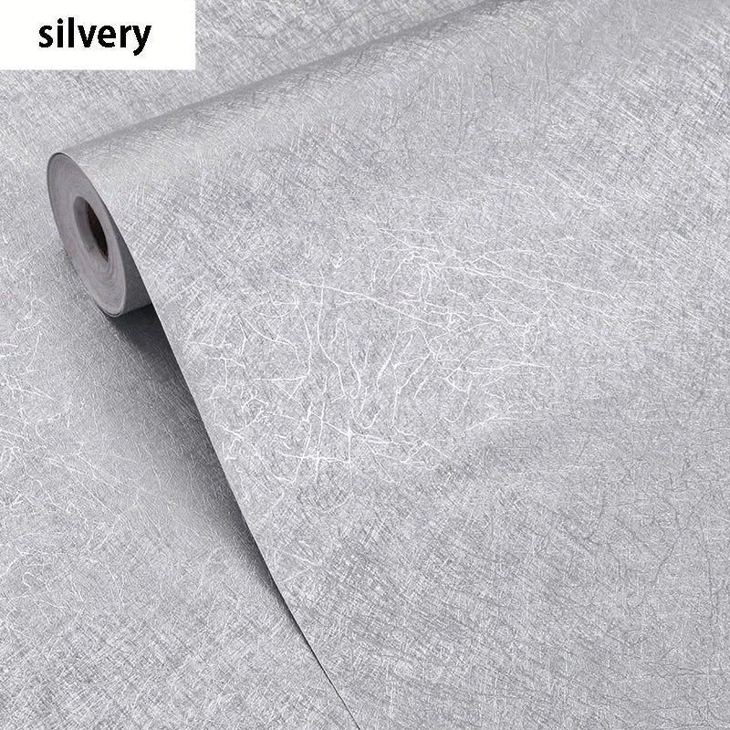 Roll of silvery embossed silk self-adhesive wallpaper being unrolled.