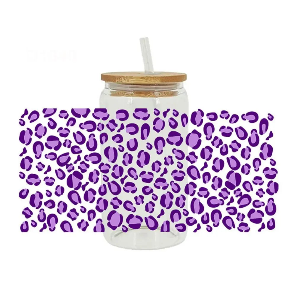 A clear glass jar with a lid and a straw wrapped in a leopard print UV DTF cup wrap sticker.