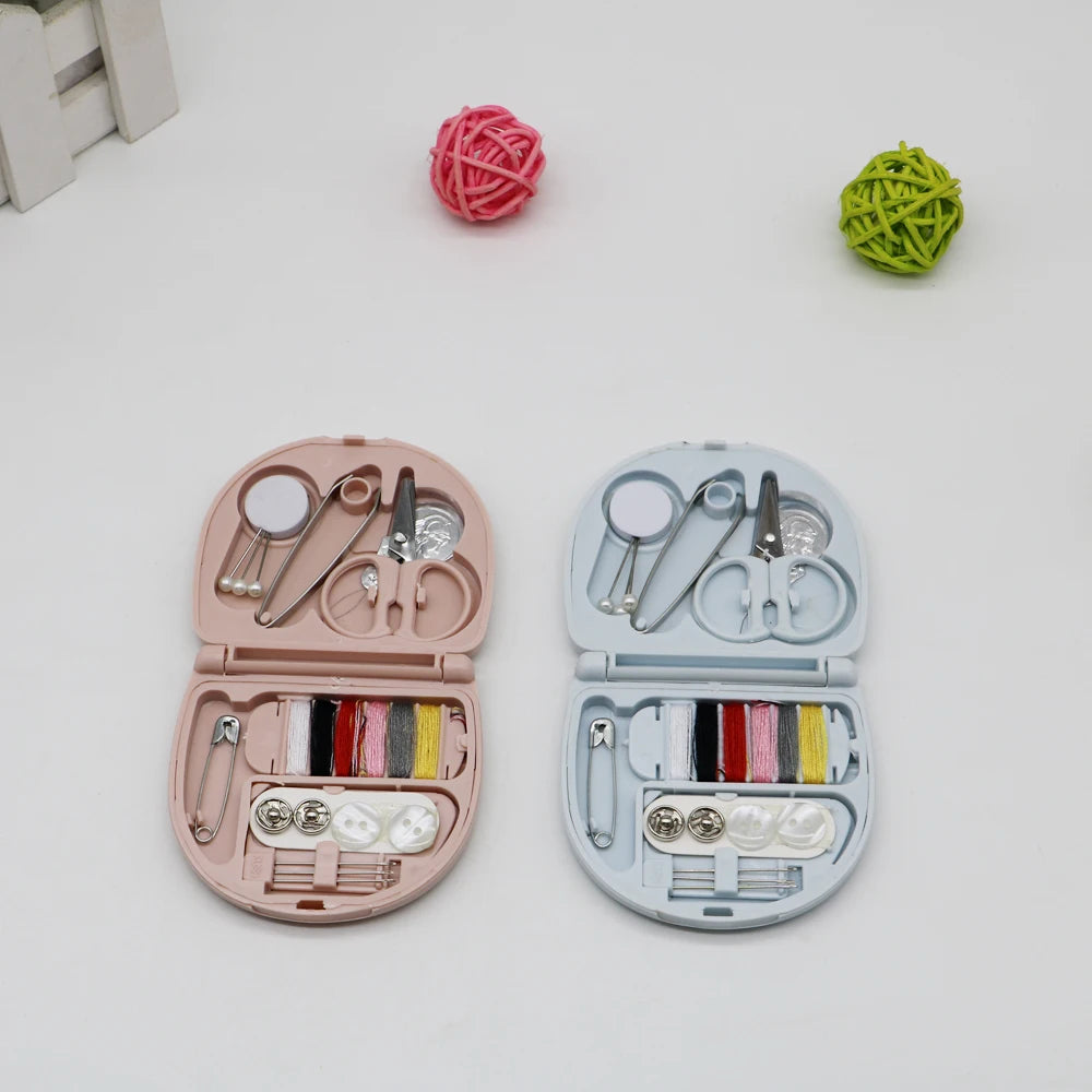 A pink portable mini sewing kit with various needles, scissors, and pins inside its lid, next to two green and pink yarn ball