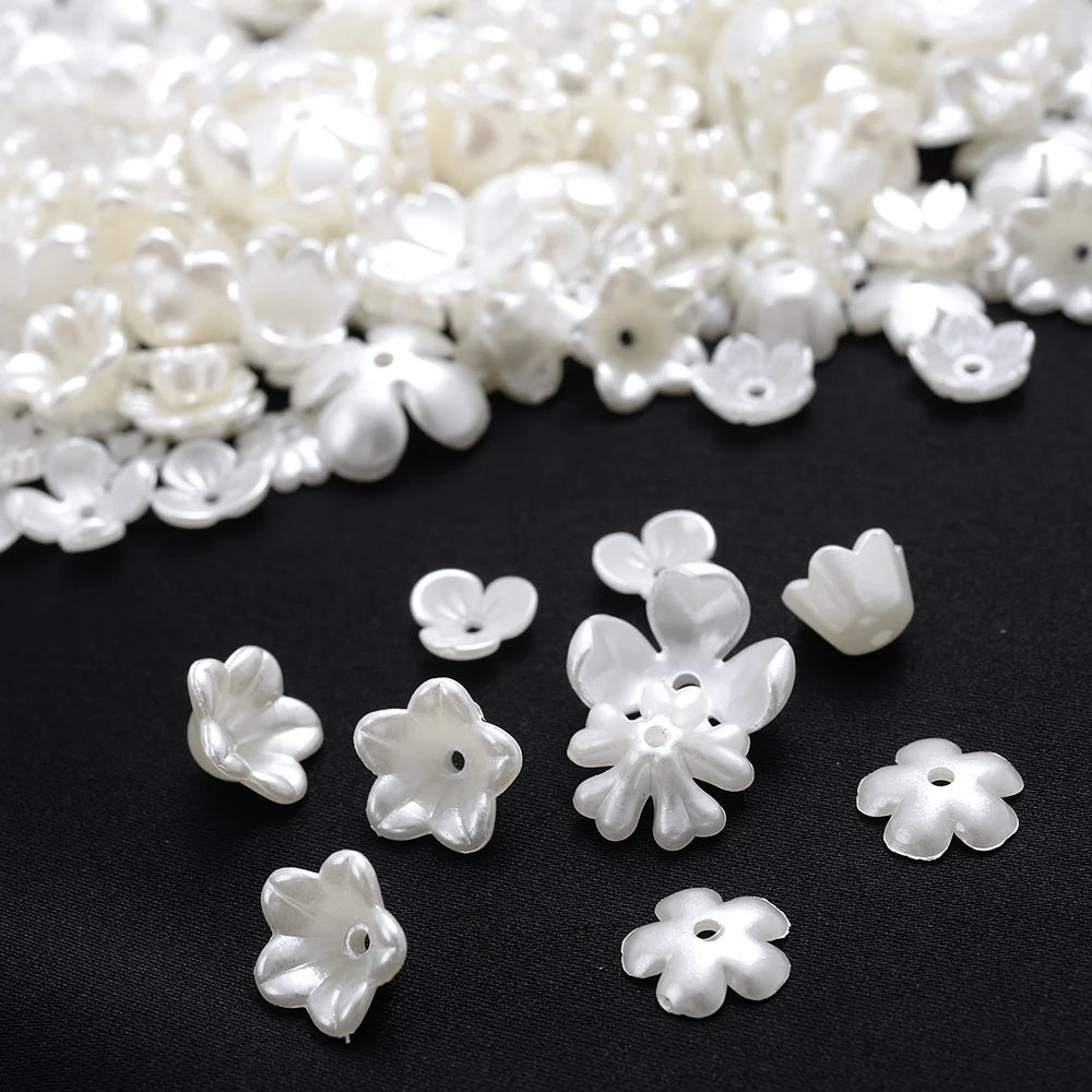 A pile of small, white acrylic pearl spacer beads for jewelry making.