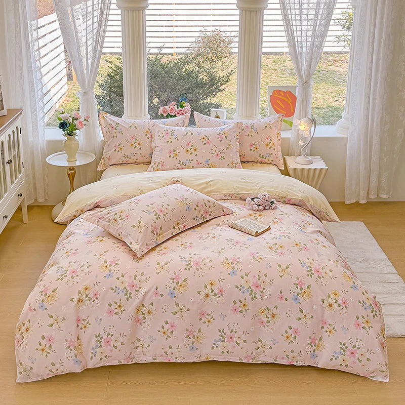 A pink floral printed duvet cover set with matching pillowcases displayed on a bed in a bright room.