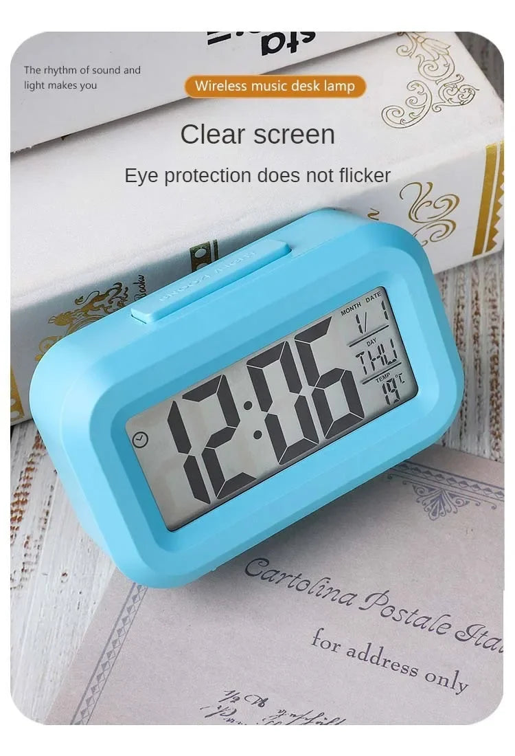 A light blue compact LED digital alarm clock with a clear screen resting on a piece of paper.