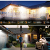 A solar motion sensor flood light illuminates a house exterior at night, demonstrating adjustable daylight lighting.