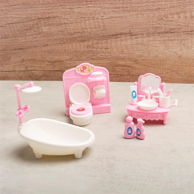 Pink miniature dollhouse furniture set including a toilet, vanity, and sink for a child's play area.