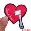 A red heart shaped iron-on patch embroidered with the text Love & Trust and a white iron tool.