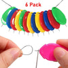 A pack of six colorful plastic needle threaders, including green, blue, yellow, and red, shown being held by a hand.