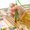 A hand holds a green magnetic color sorting maze board with a peg, demonstrating a Montessori wooden learning toy.