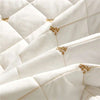 Close-up of a white quilted bed skirt featuring gold embroidery on the fabric.