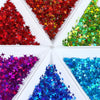 A collection of shiny holographic star sequins in various colors like red, green, purple, and blue arranged in a white box.