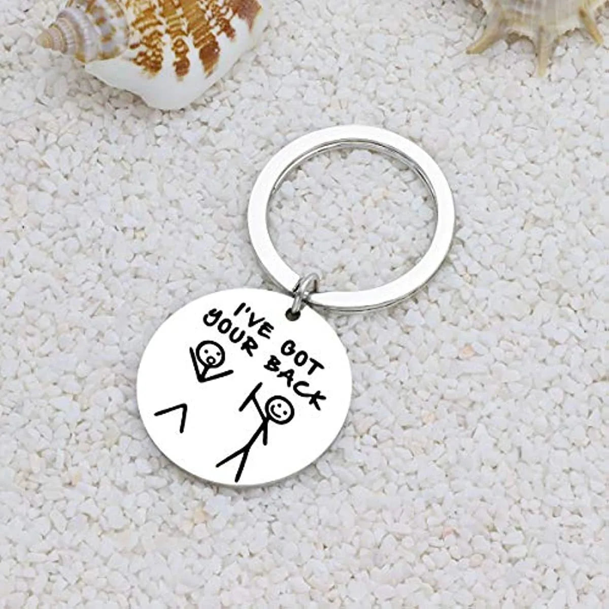 A silver stainless steel keychain with the text I've got your back engraved on a circular tag, resting on a white textured su