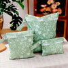 A set of light green reusable waterproof wet bags with a floral pattern displayed on a table.