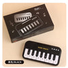 A black mini 15-key electronic keyboard piano is shown in its box and standalone form.