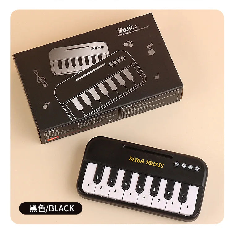 A black mini 15-key electronic keyboard piano is shown in its box and standalone form.
