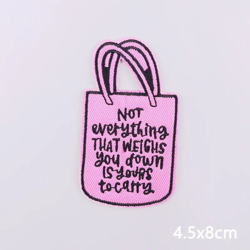 Pink embroidered tote bag with black handles featuring the text Not everything that weighs you down is your to carry