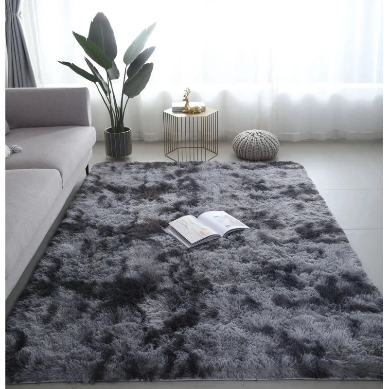 A gray luxury velvet plush carpet placed in a bright living room with a potted plant and natural light.