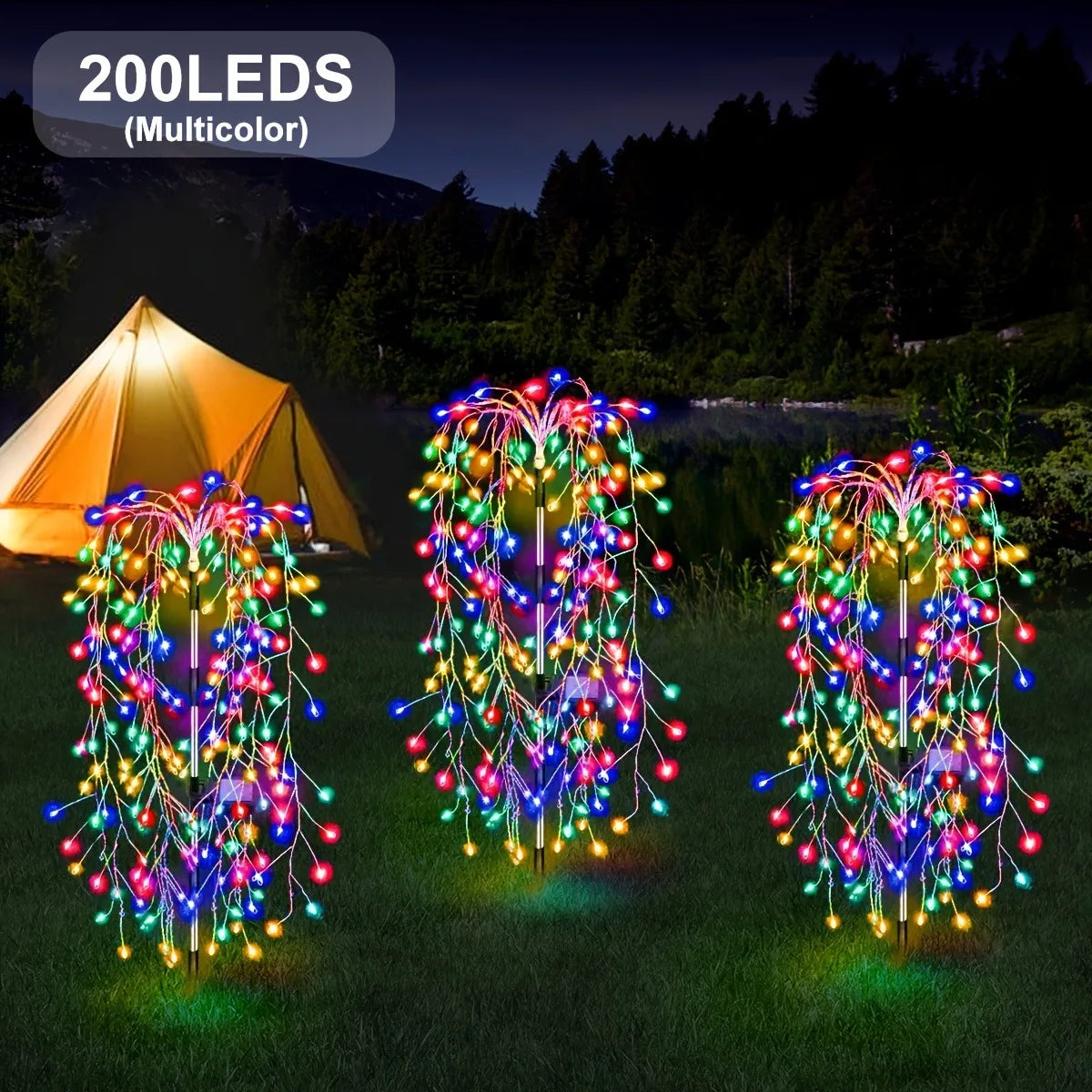 Three strands of multicolor LED lights resembling willow trees illuminating a grassy outdoor scene.