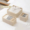 Three light beige foldable drawer organizer boxes filled with various folded underwear, bras, and socks.