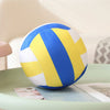 A blue and yellow simulation volleyball plush toy resting on a light green surface.