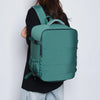 A teal travel backpack is shown being worn by a person against a white background.