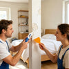 A man and a woman are repairing a crack in a white wall using a wall repair paste kit.