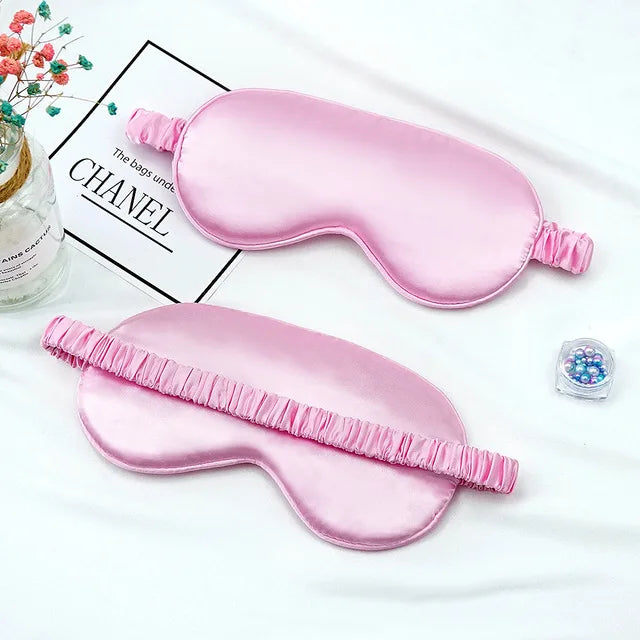Pink silk sleep mask with a ruffled edge displayed on a white background.