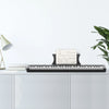 A black 61-key digital piano with a stand, bench, headphones, and pedal placed on a white cabinet.