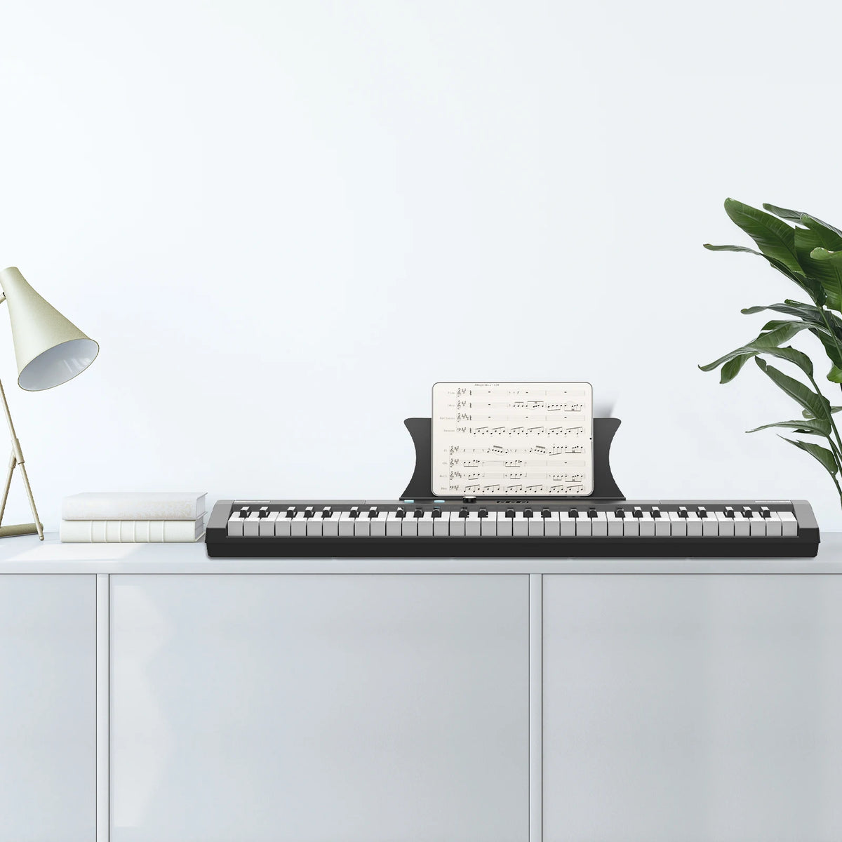 A black 61-key digital piano with a stand, bench, headphones, and pedal placed on a white cabinet.