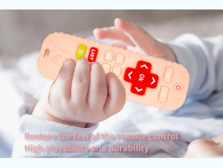 A baby's hand holds an orange silicone teether toy shaped like a remote control with buttons and a list feature.