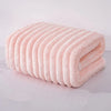 A rolled pink microfiber towel with ribbed texture is shown on a white surface.