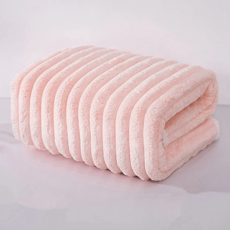A rolled pink microfiber towel with ribbed texture is shown on a white surface.