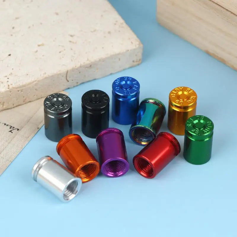 A set of four colored bullet shell tire valve stem caps displayed on a light blue surface.