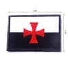 A rectangular embroidered patch featuring a red cross on a white field, mounted on black fabric with hook and loop backing.