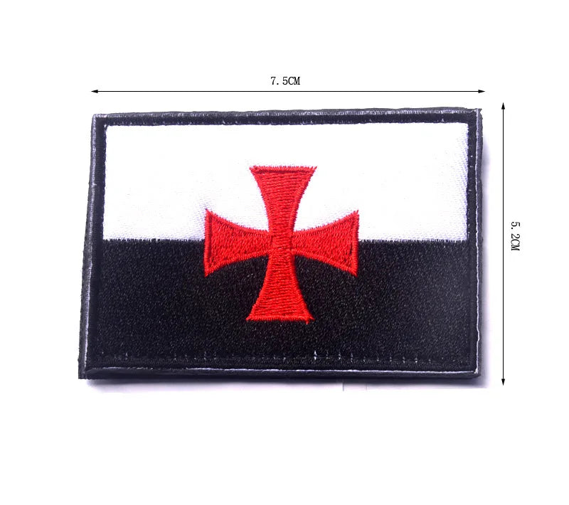 A rectangular embroidered patch featuring a red cross on a white field, mounted on black fabric with hook and loop backing.