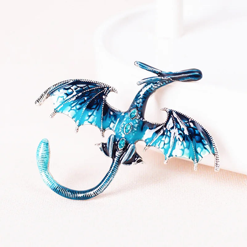 A blue enamel dragon brooch with silver accents and rhinestone details displayed on a white background.
