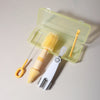 A silicone baby bottle cleaning set with a light green case and three yellow brushes.