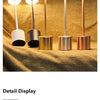 A row of five gold and silver finish LED table lamps with white light bulbs displayed on a textured fabric.