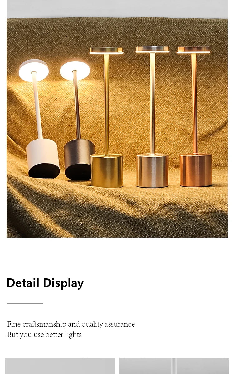 A row of five gold and silver finish LED table lamps with white light bulbs displayed on a textured fabric.