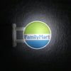 A round magnet featuring the FamilyMart logo with a bright lime green background and blue text on a dark surface.