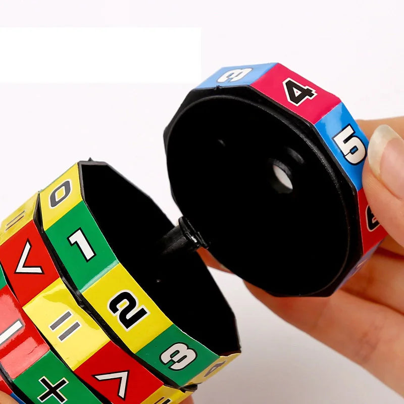 A hand holds a colorful Montessori math cube toy showing numbers and arithmetic symbols.