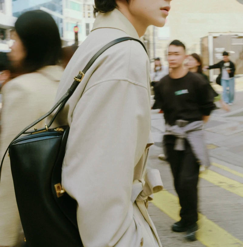 A close-up shot of a beige leather jacket and a black leather crossbody bag with a gold lock.