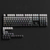 A close-up view of a black PBT double-shot keycap set with gradient colored keycaps on a dark background.