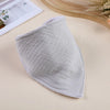 A soft, light gray cotton baby bib is shown lying on a beige surface.