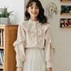 A woman models a beige vintage lace long sleeve blouse with ruffled details and a white skirt.