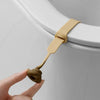 A hand is lifting the handle of a beige hands-free toilet lid lifter.