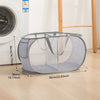 A gray folding mesh laundry basket with handles is shown next to a washing machine.
