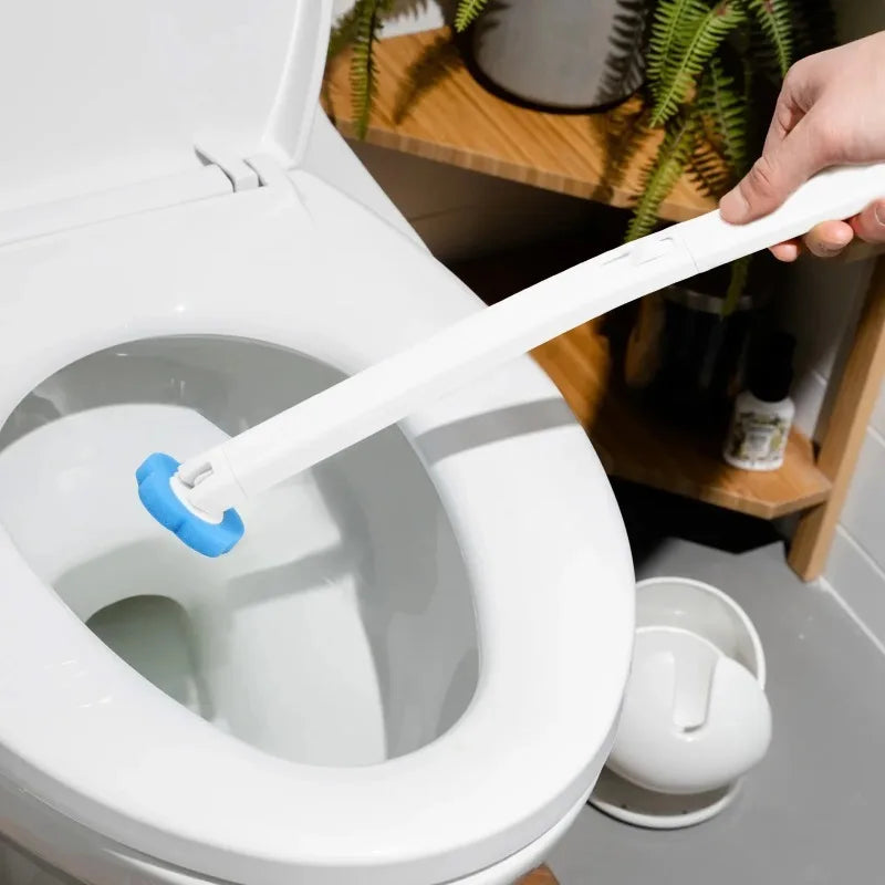 A hand is holding a white disposable toilet brush replacement head inside a white toilet bowl.