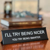 A black desk sign with white text that reads I'll try being nicer you try being smarter